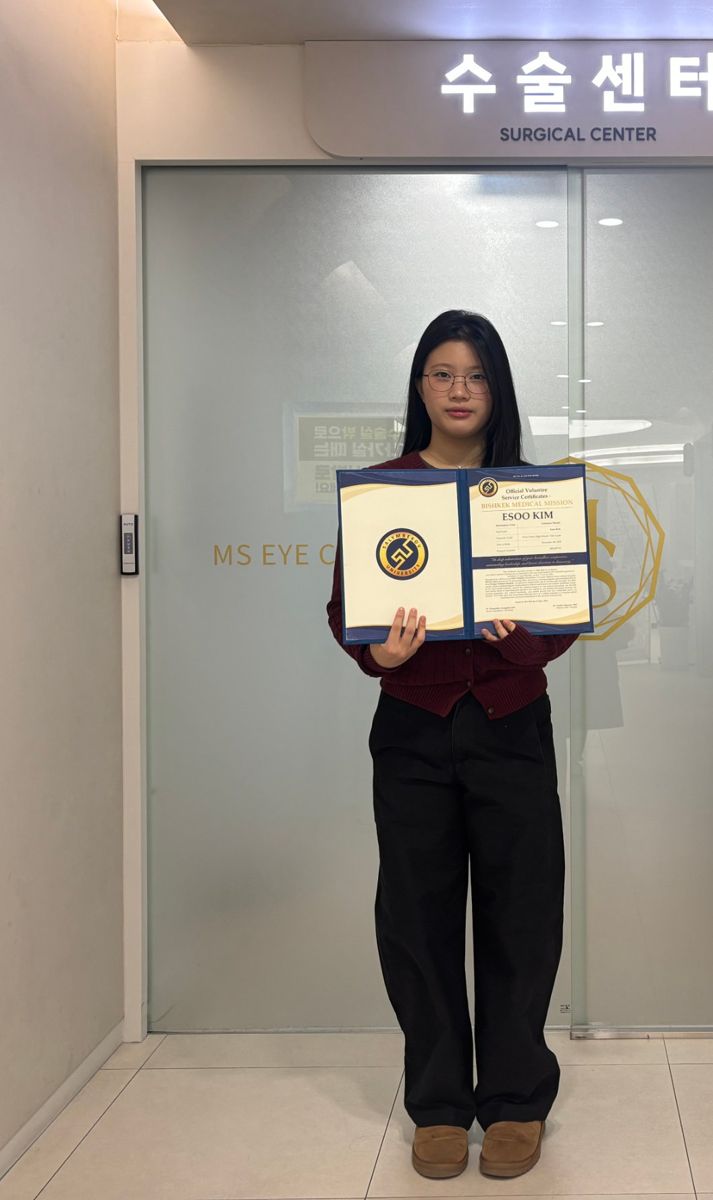 Esoo holding her Bishkek Medical Mission certificate outside a surgical center