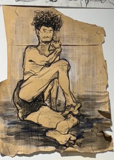 Seated figure drawn in charcoal and wash on torn kraft paper