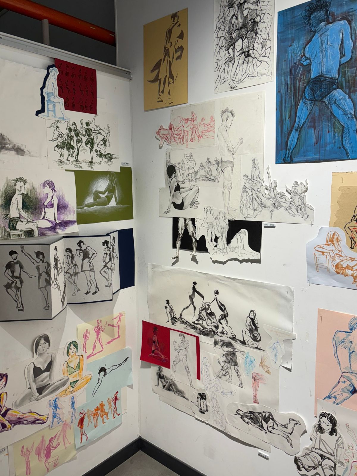 Corner wall covered in figure drawings in ink, charcoal and color