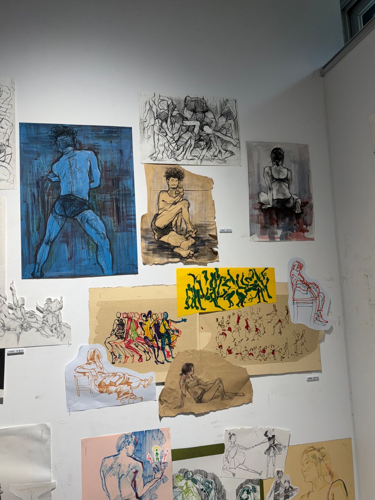 Corner of a studio wall layered with gesture drawings and ink studies