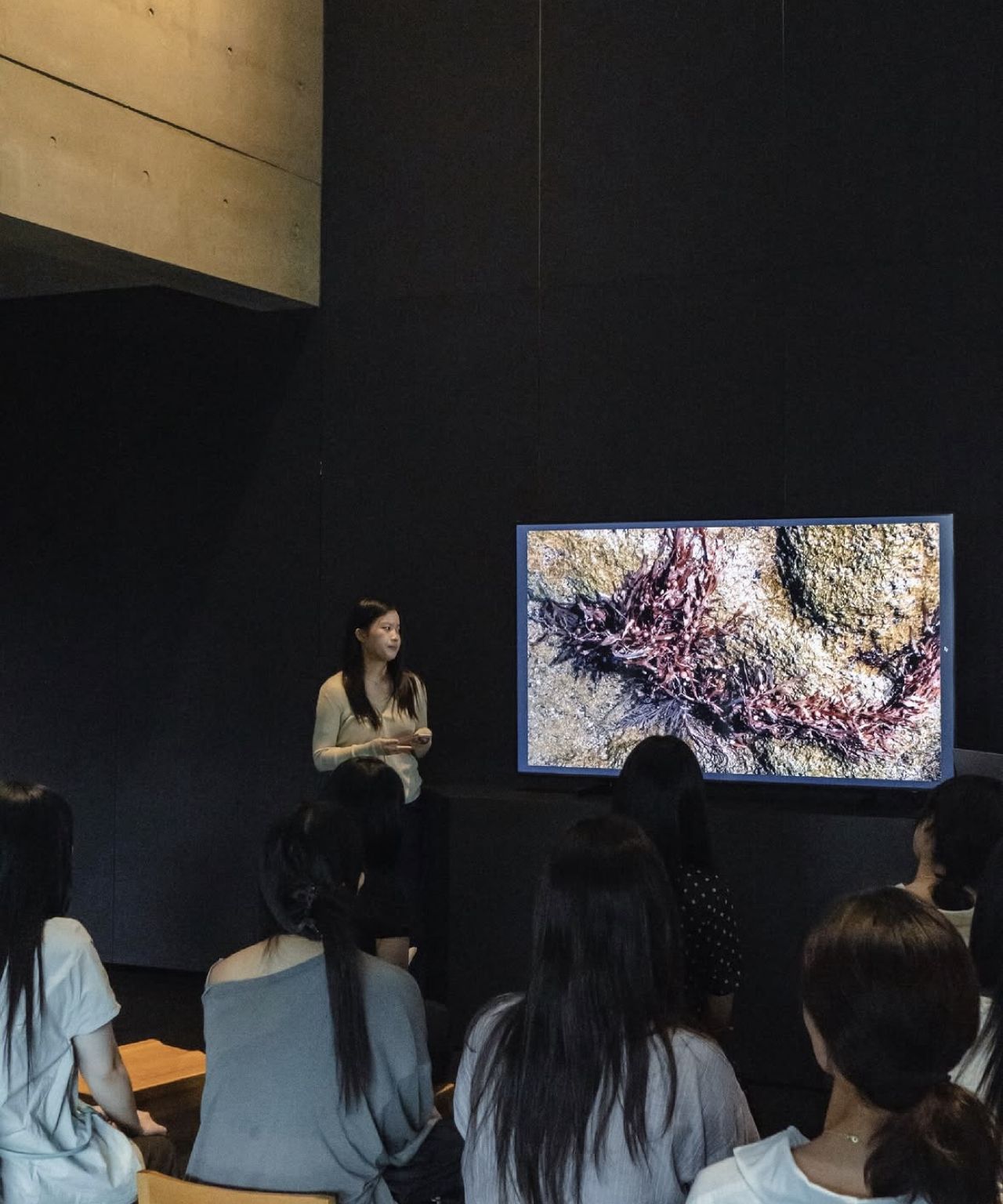 Esoo presenting beside a screen showing seaweed on rock